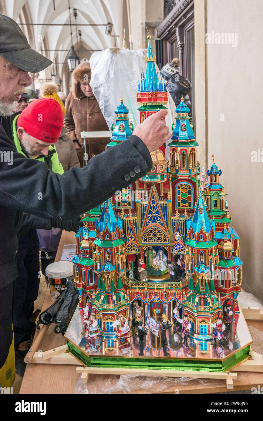 Der Künstler vervollständigt seine Szopka (Weihnachtskrippe), die bei der Eröffnung des jährlichen Wettbewerbs im Dezember in der Liste des UNESCO-Weltkulturerbes in den Arkaden von Sukiennice (Tuchhalle), dem Hauptmarkt in Kraków, Polen, gezeigt wird Stockfoto