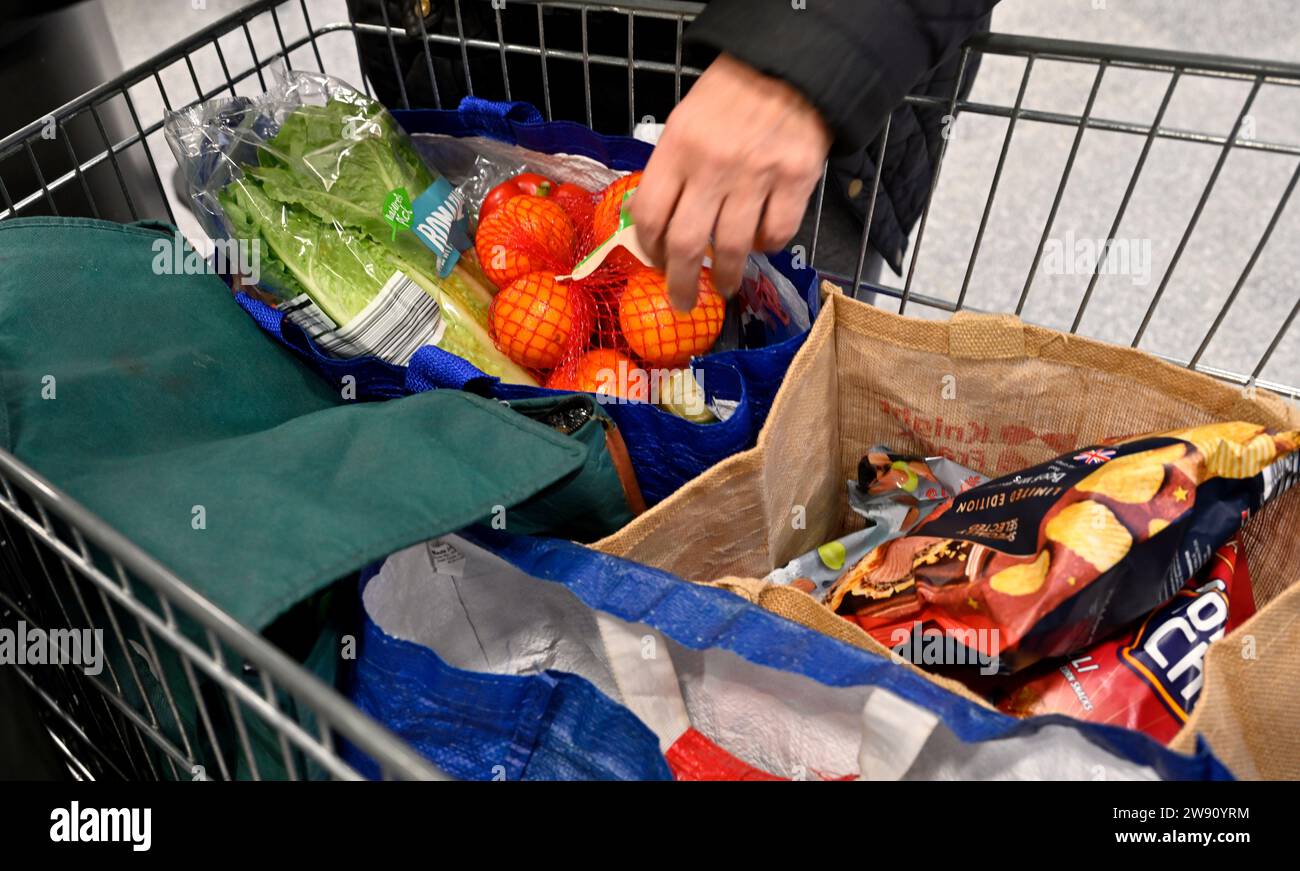 Der Kunde verpackt Lebensmittel in selbst gelieferte Recyclingbeutel in einem Einkaufswagen für den Supermarkt Stockfoto