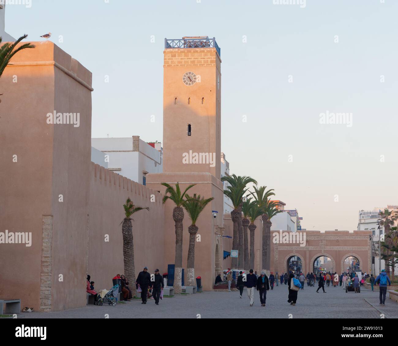 Hauptstraße mit Uhrenturm voller Menschen am Abend in Essaouira, Marokko. Dezember 2023 Stockfoto