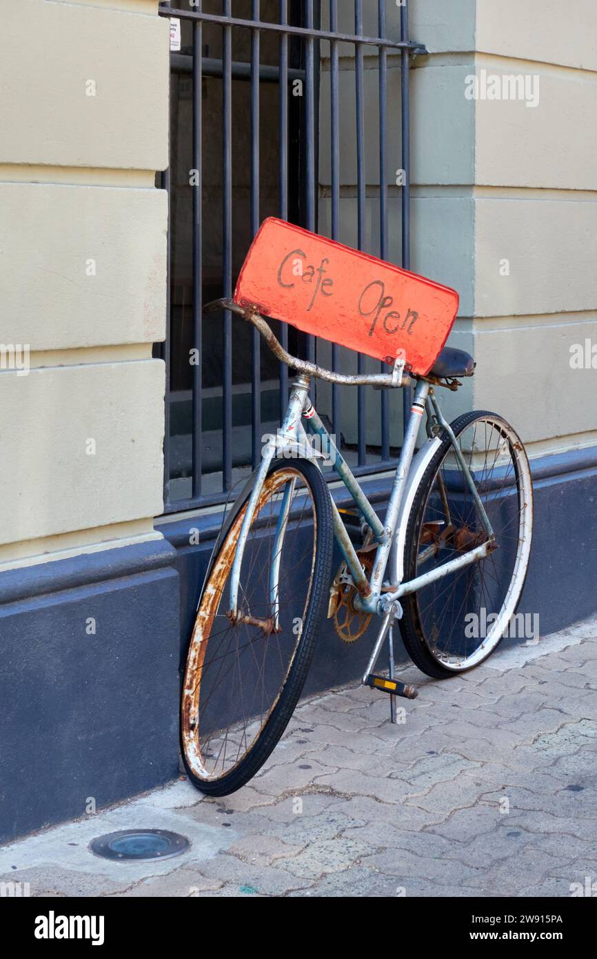 Ein vertikales Bild eines Cafe Open-Schilds, das an einem alten Fahrrad auf der Straße in Fremantle, Perth, Western Australia angebracht ist Stockfoto