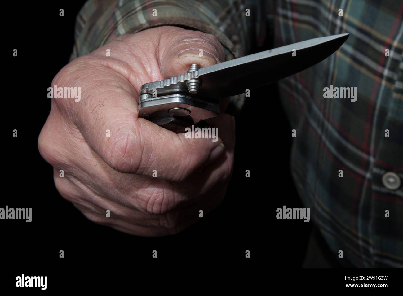 Die Hand eines Mannes öffnet ein gefährliches einhändiges Messer. Diese sind in Deutschland illegal. Warnung vor rechtlichen Konsequenzen. Stockfoto