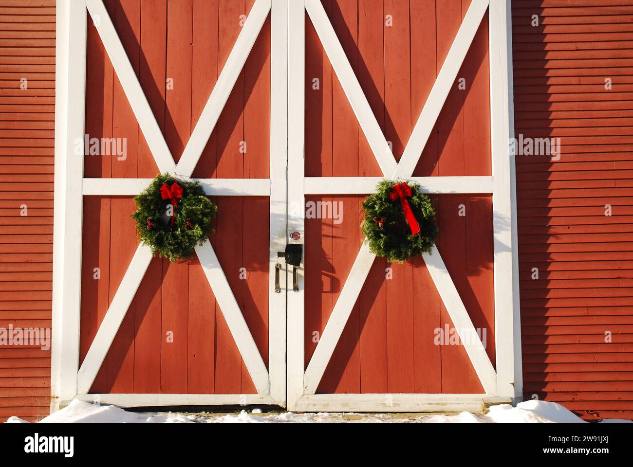 Zwei Weihnachtskränze hängen im Winter an den Türen einer roten New England Scheune Stockfoto