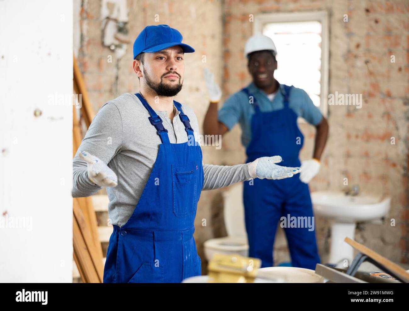 Vorarbeiter schreit nach dem verwirrten Arbeiter auf der Baustelle Stockfoto