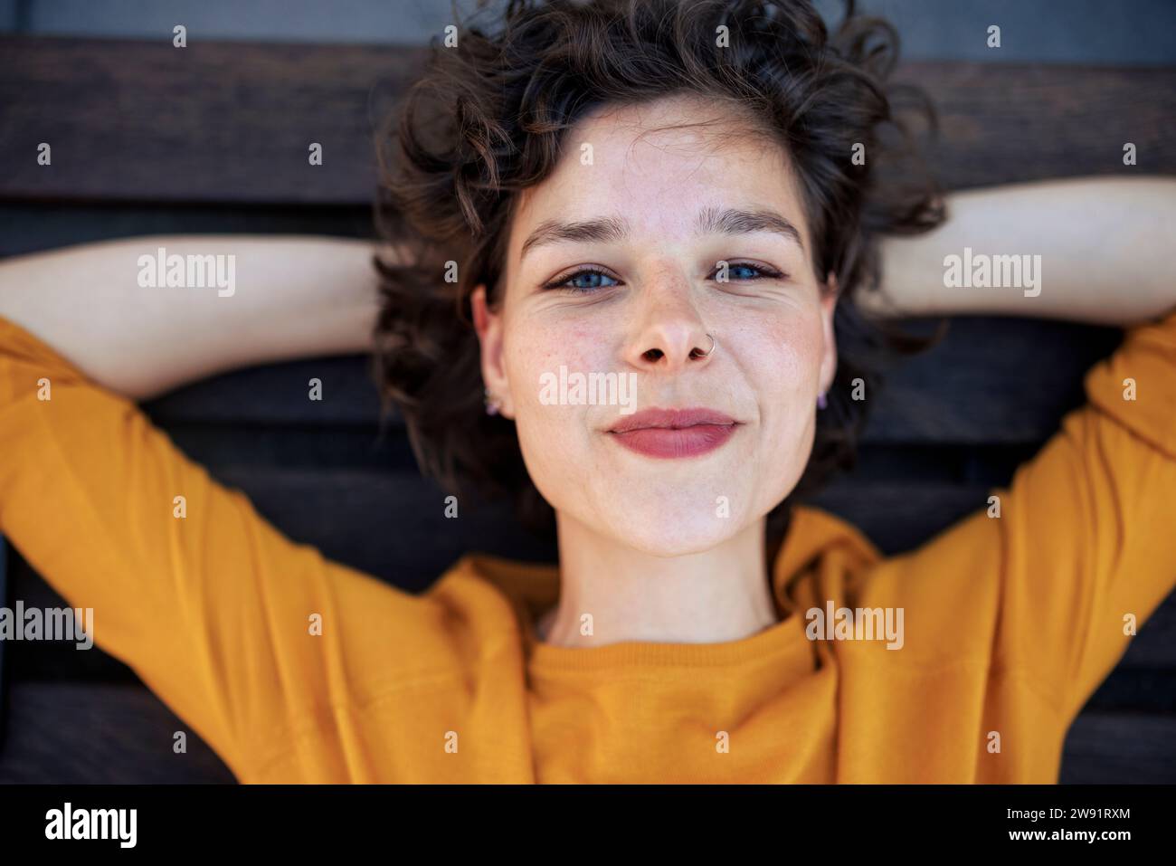 Lächelnde Frau mit Händen hinter dem Kopf Stockfoto