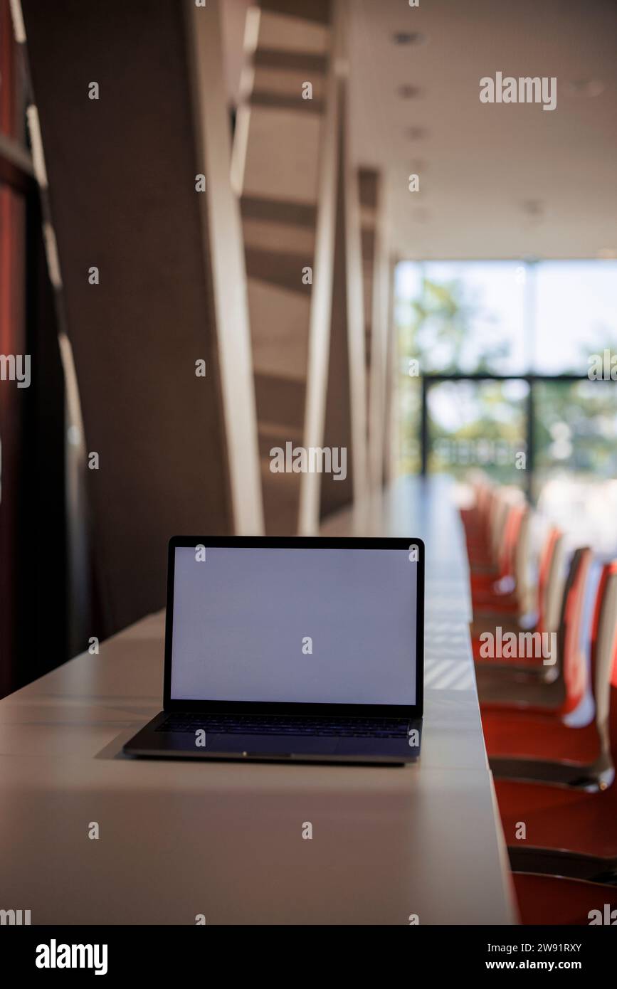 Laptop mit leerem Bildschirm auf dem Tisch in der Bürocafeteria Stockfoto