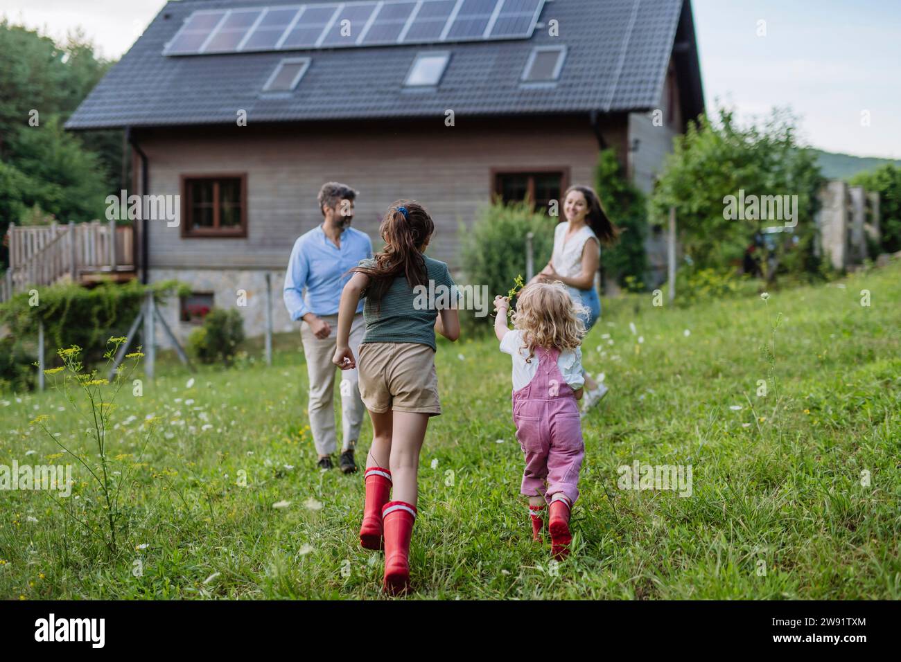 Glückliche Mädchen, die im Garten eines nachhaltigen Familienhauses laufen Stockfoto