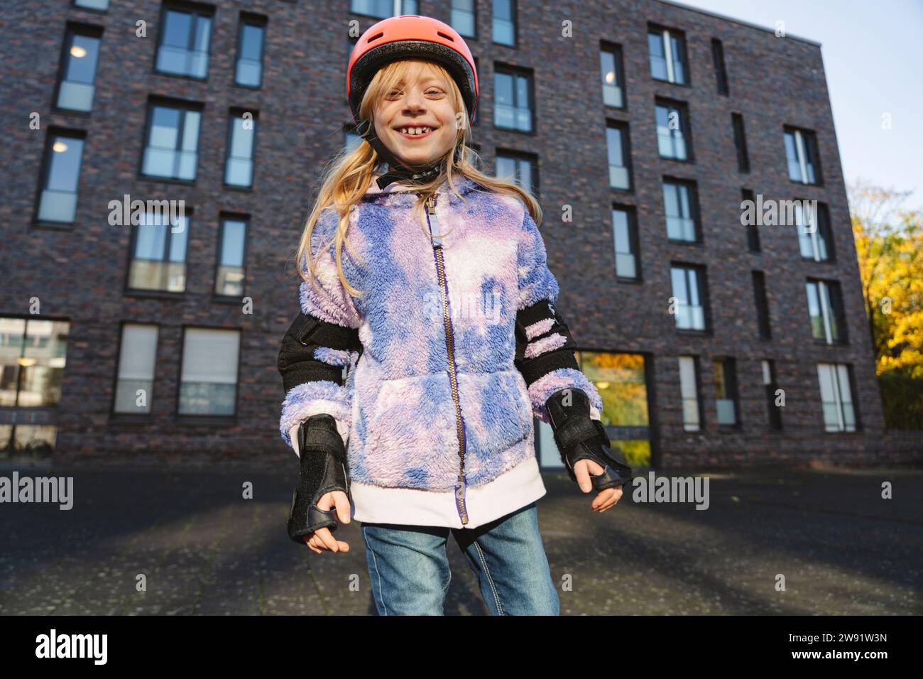 Lächelndes Mädchen mit Schutzkleidung, das vor dem Gebäude steht Stockfoto