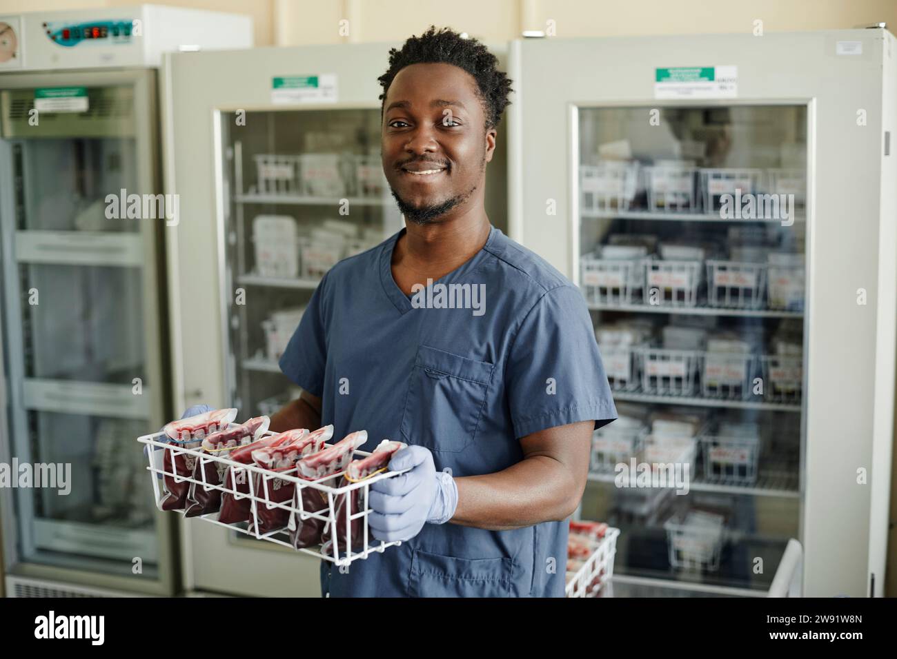 Lächelnder Labortechniker, der Blutbeutel hält Stockfoto