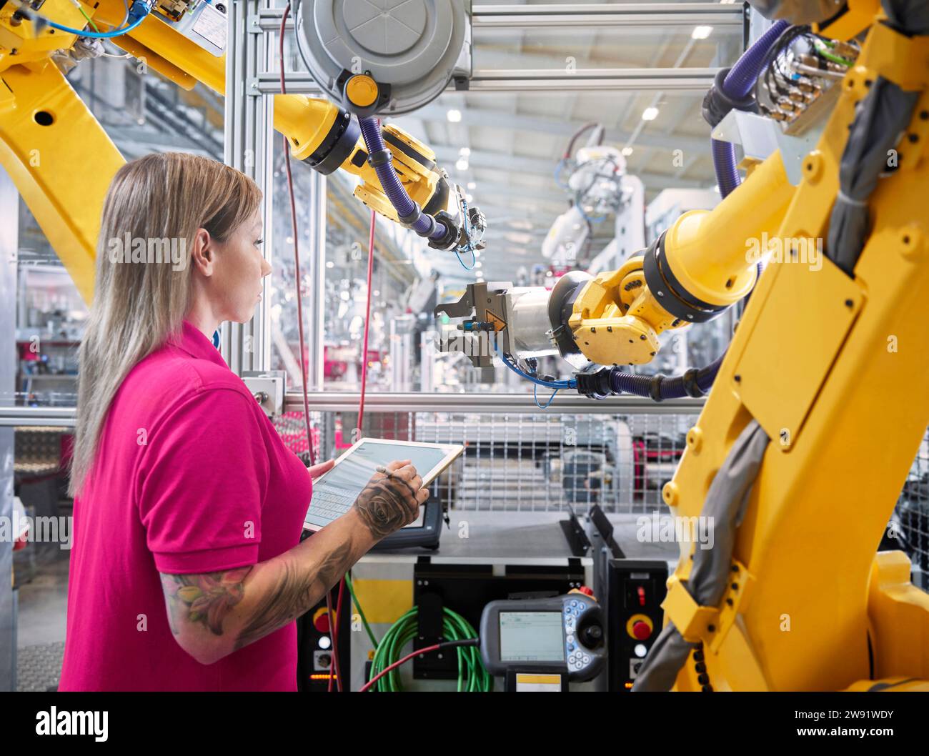 Techniker, der Roboterarme untersucht und Tablet-PCs in der Industrie hält Stockfoto