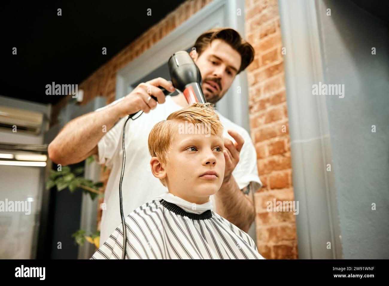 Friseur föhnt die Haare des Kunden im Salon Stockfoto