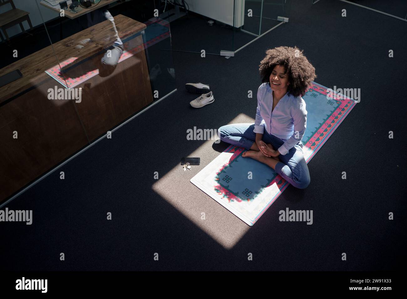 Geschäftsfrau meditiert auf Yogamatte im Büro Stockfoto