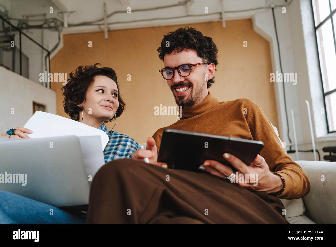 Ein lächelnder Illustrator sitzt mit einem Kollegen im Büro Stockfoto