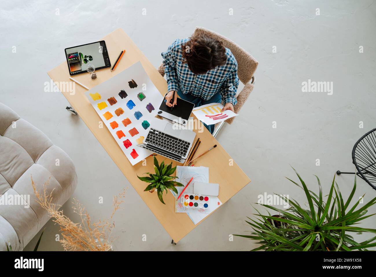 Junger Illustrator, der an drahtlosen Technologien am Schreibtisch im Büro arbeitet Stockfoto