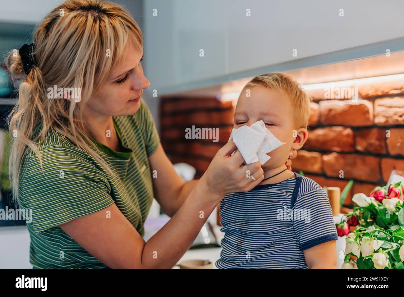 Mutter wischt dem Sohn zu Hause die Nase ab Stockfoto