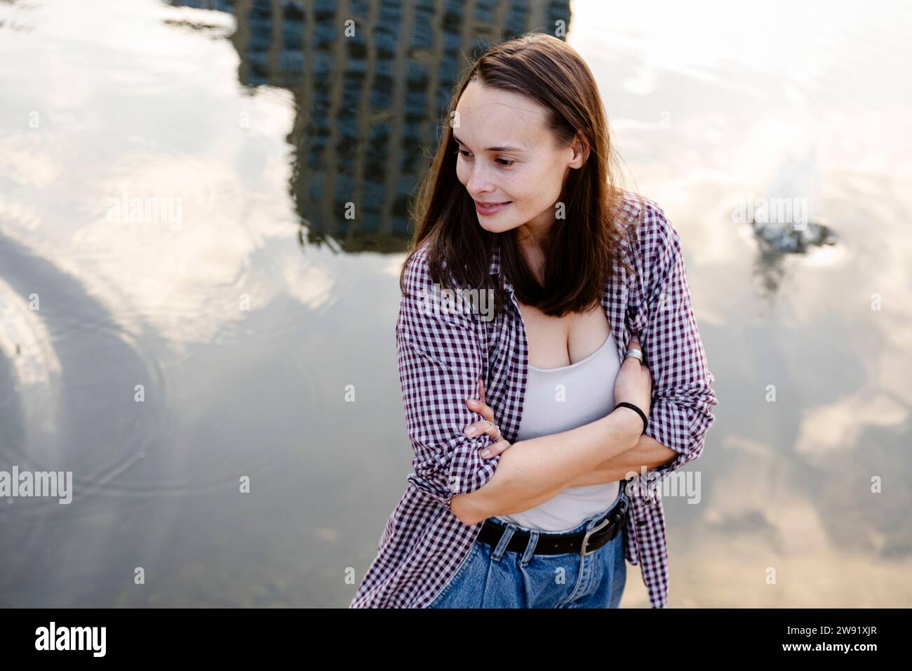Lächelnde Frau mit überkreuzten Armen in der Nähe des Sees Stockfoto
