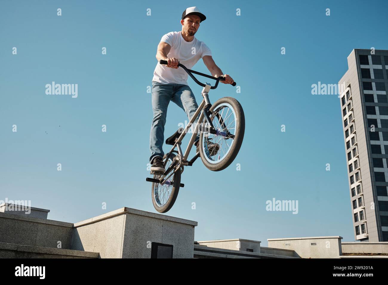 Mann springt mit dem BMX-Fahrrad unter dem Himmel an sonnigen Tagen Stockfoto