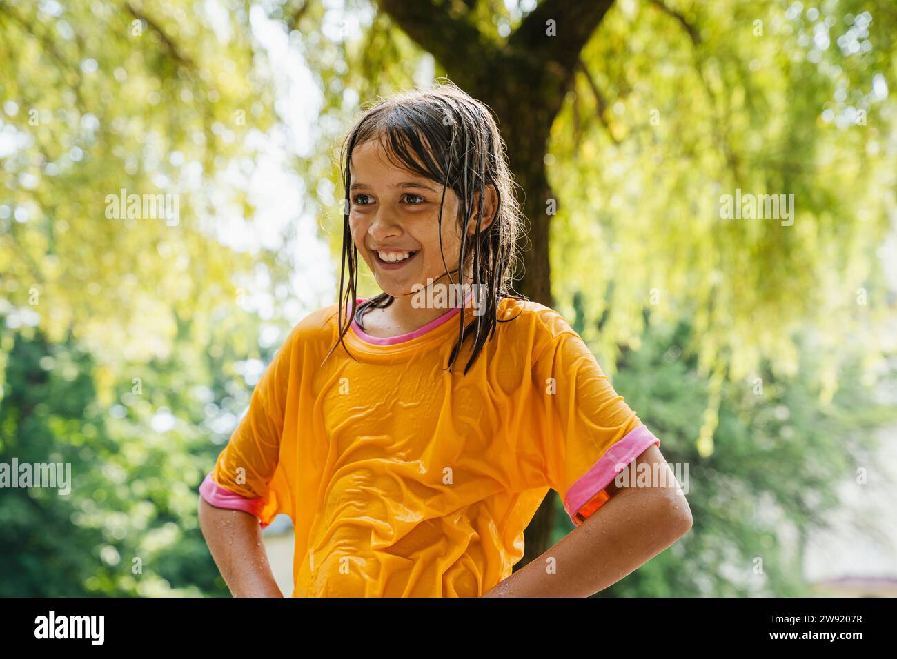 Lächelndes Mädchen in nassen Kleidern im Park Stockfoto