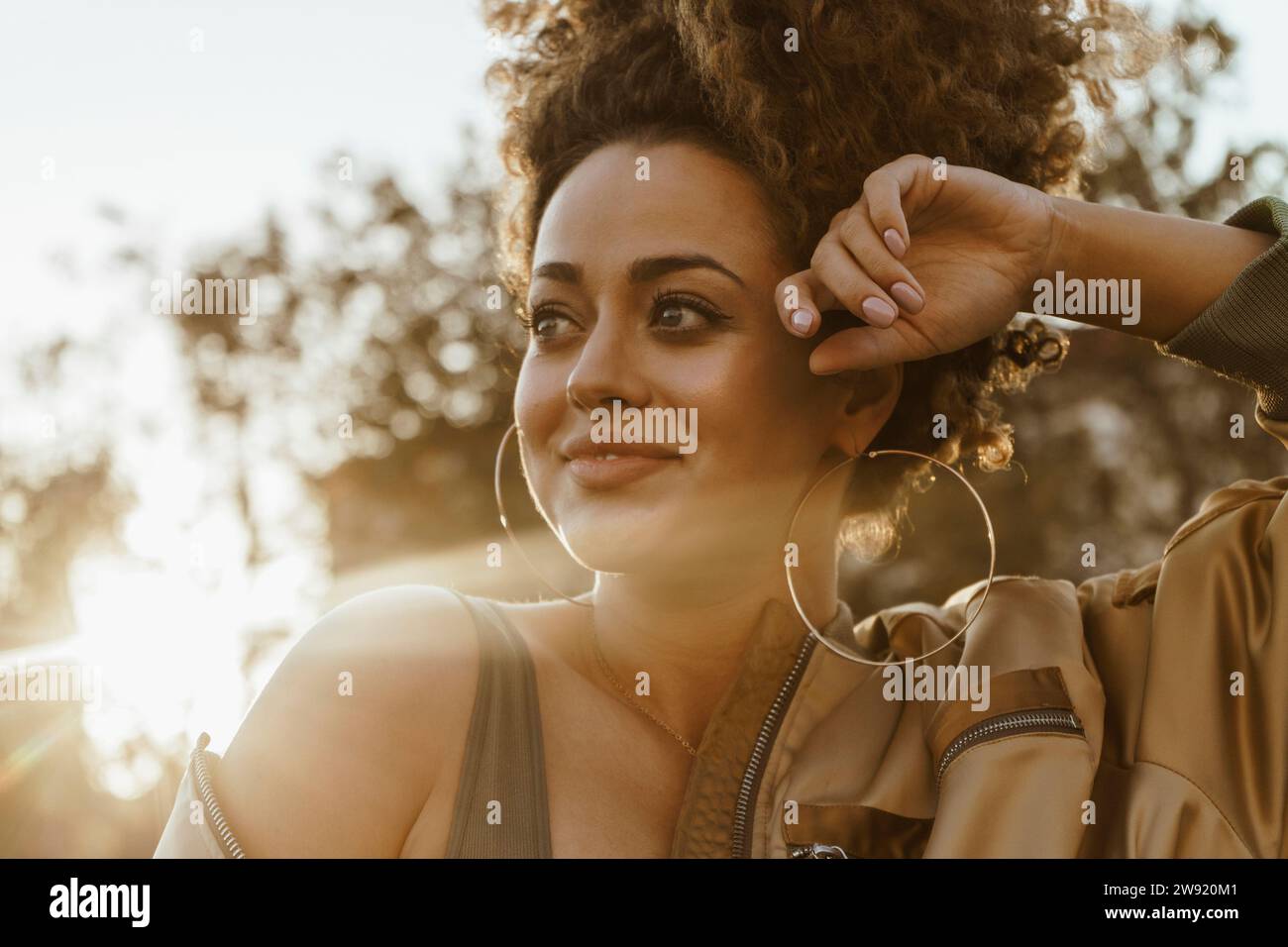 Glückliche Frau trägt Creolen bei Sonnenuntergang Stockfoto