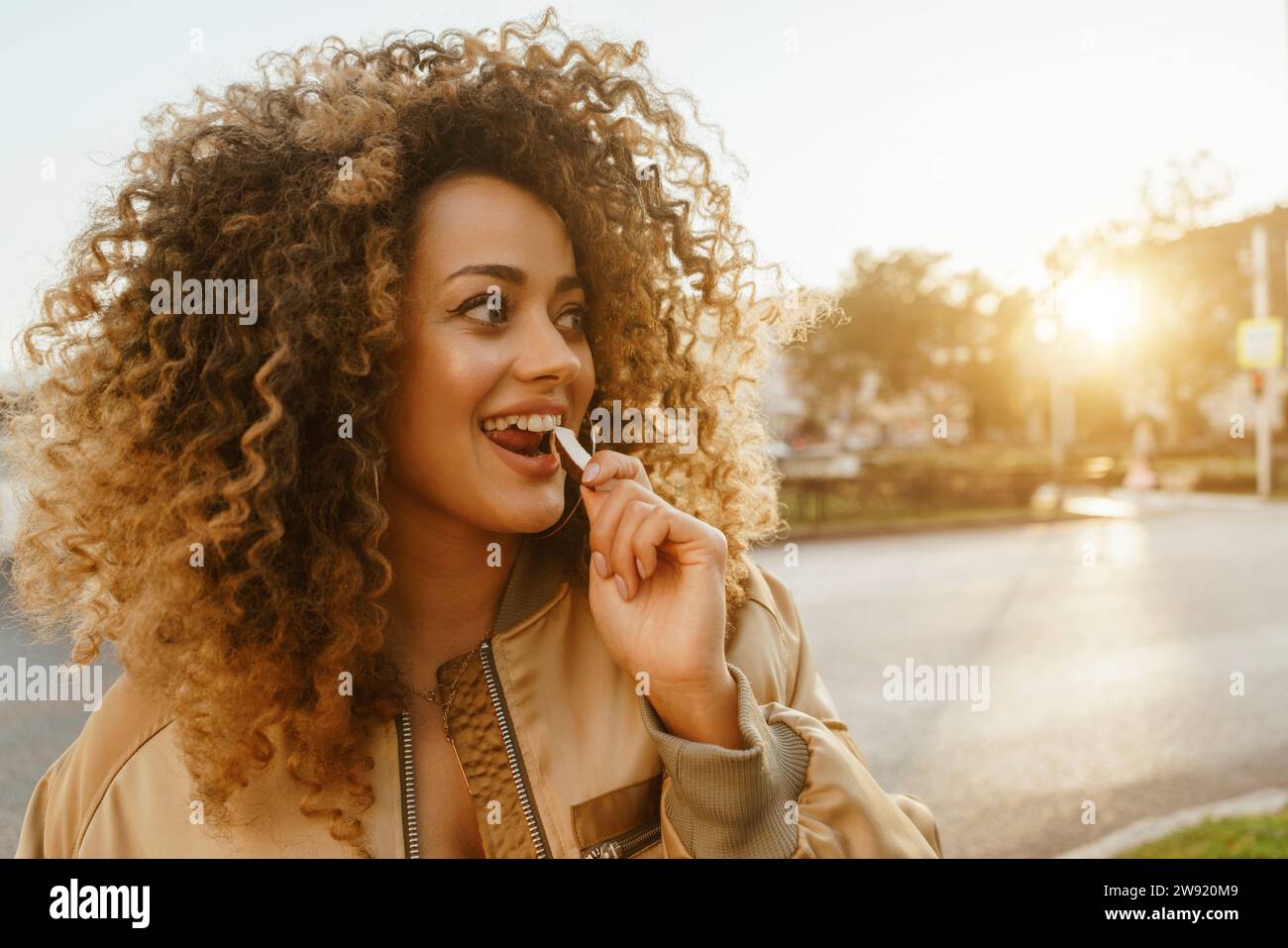 Glückliche Frau mit Löffel im Mund auf der Straße Stockfoto