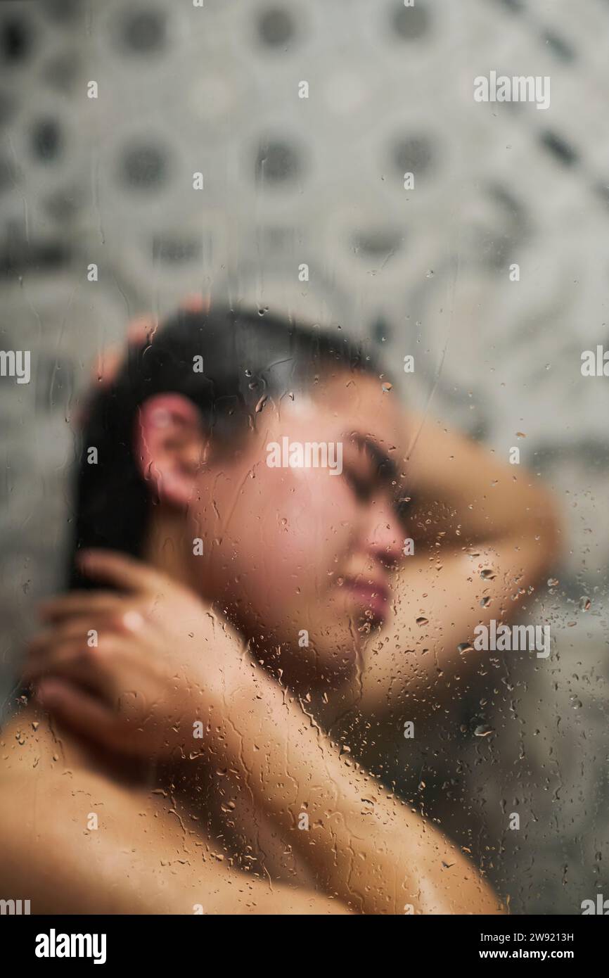 Eine junge Frau, die durch Glas baden lässt Stockfoto