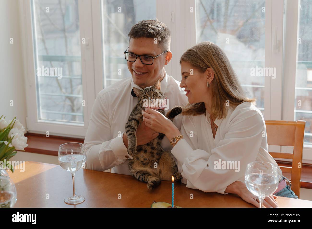 Ein junges Paar, das zu Hause Katzengeburtstag feiert Stockfoto