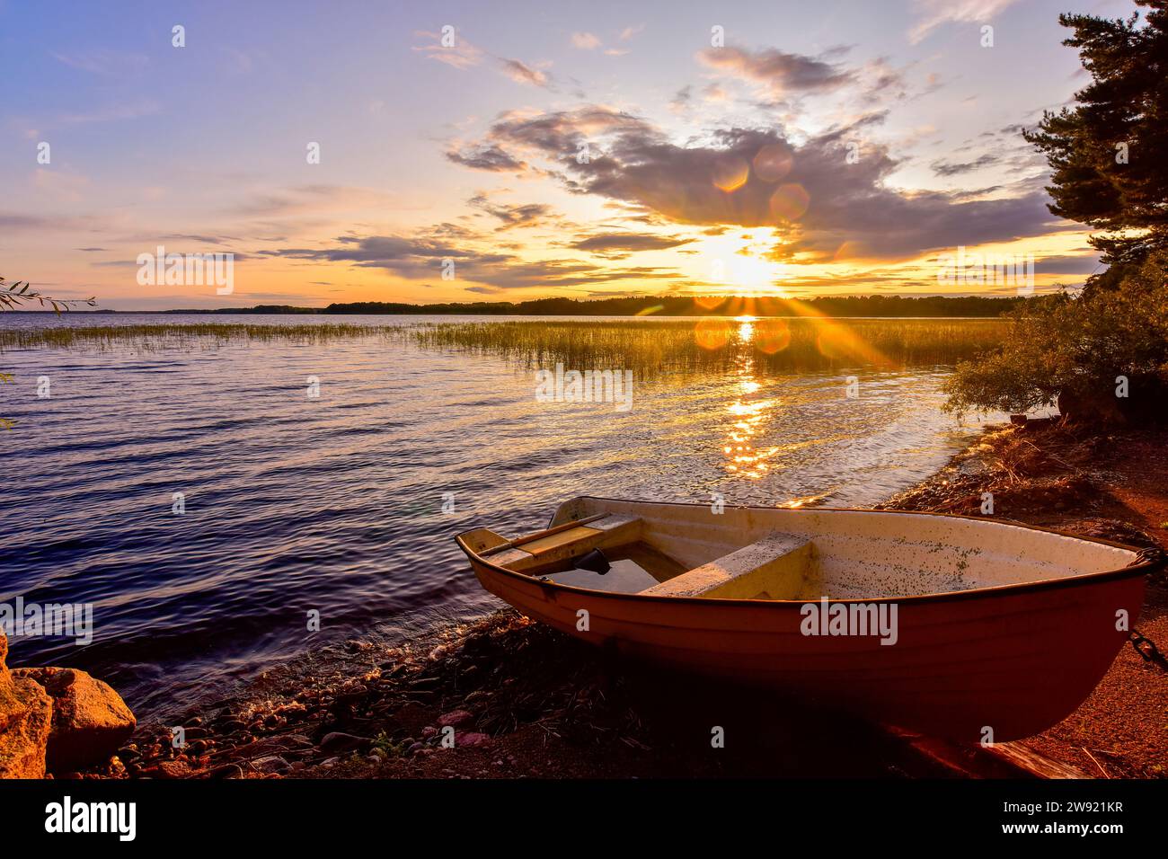 Schweden, Gavleborg County, Hedesunda, leeres Ruderboot, das bei Sonnenuntergang auf Lakeshore liegt Stockfoto
