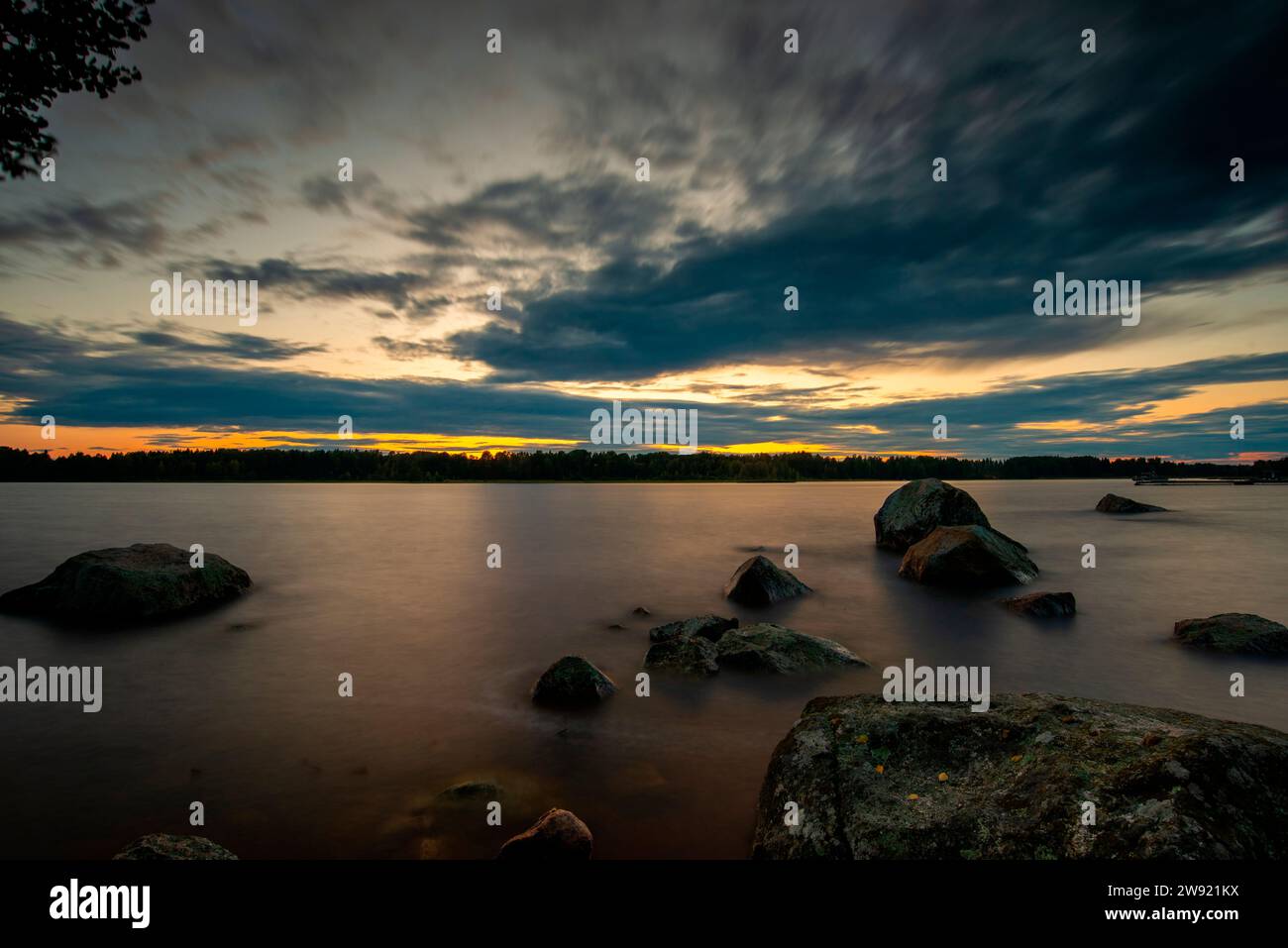 Schweden, Gavleborg County, Hedesunda, Wolken über den Felsen des Seeufers in der Abenddämmerung Stockfoto