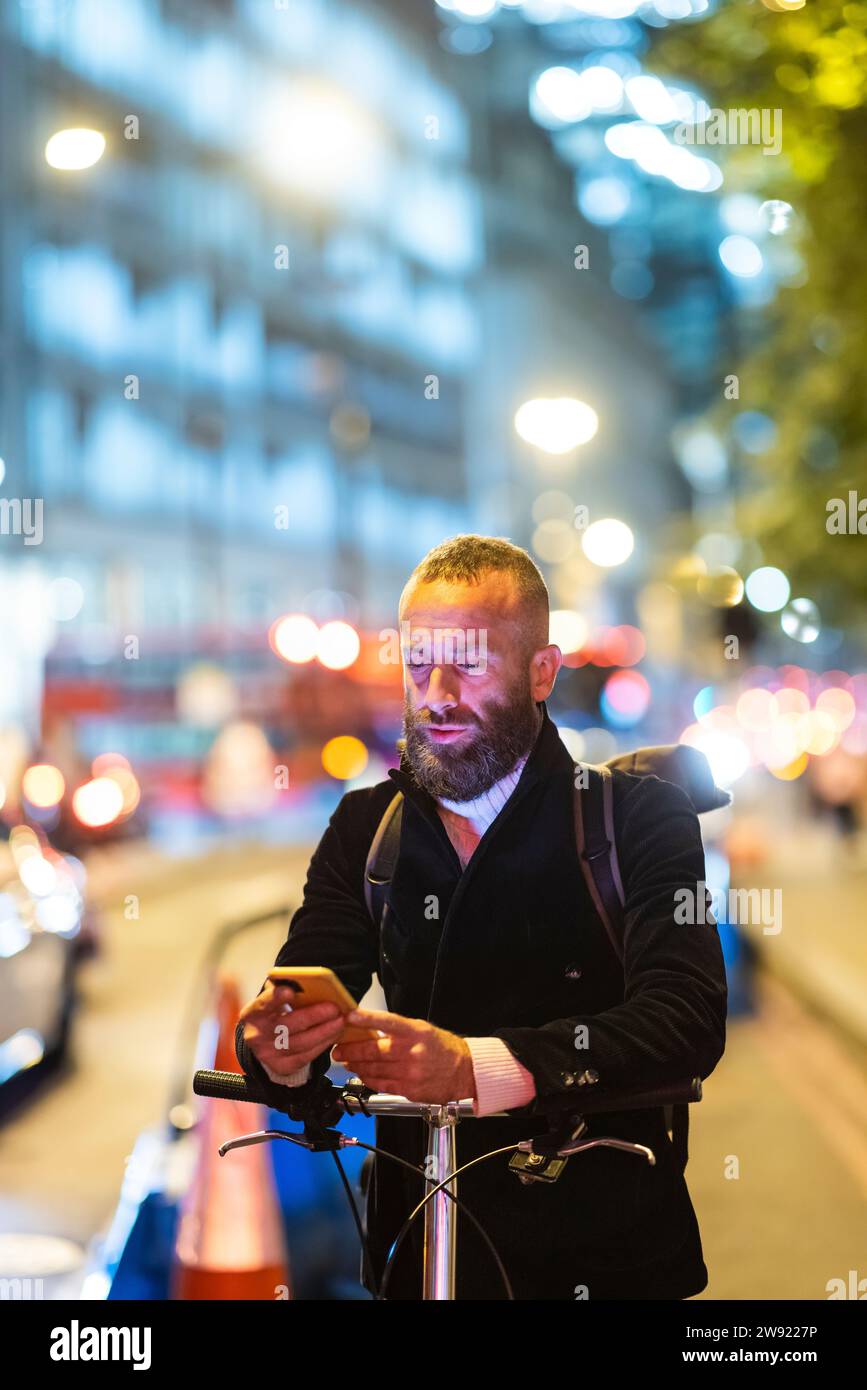 Pendler mit Mobiltelefon in der Stadt bei Nacht Stockfoto