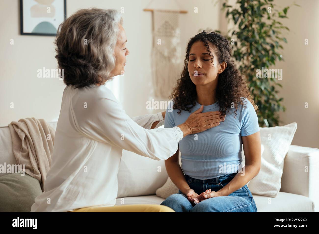 Psychologin, die dem gestressten Patienten in der Therapiesitzung zu Hause Atemübungen beibringt Stockfoto