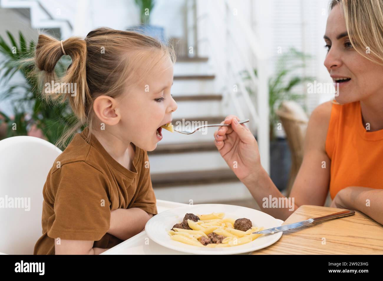 Mutter füttert dem Jungen Pasta am Esstisch zu Hause Stockfoto