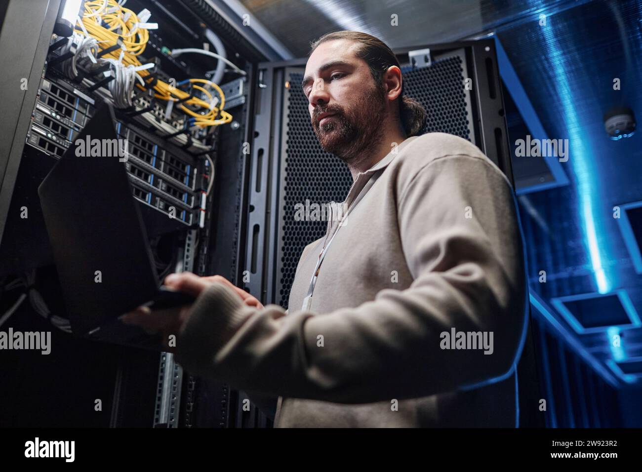 Techniker, der an Laptop in der Nähe von Geräten im Serverraum arbeitet Stockfoto