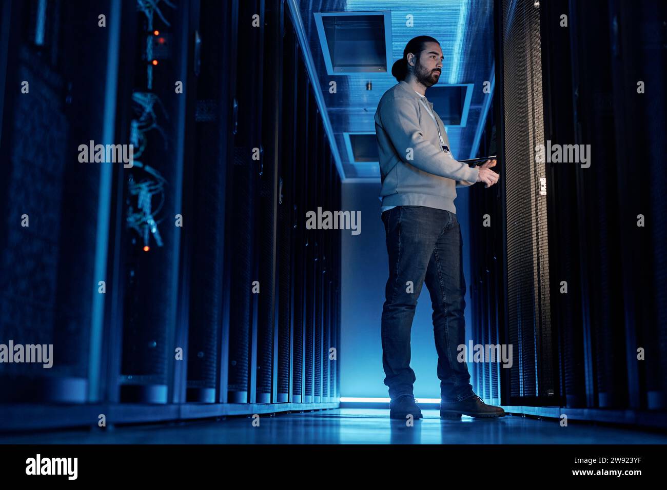 Junger IT-Ingenieur, der Supercomputer im Serverraum untersucht Stockfoto