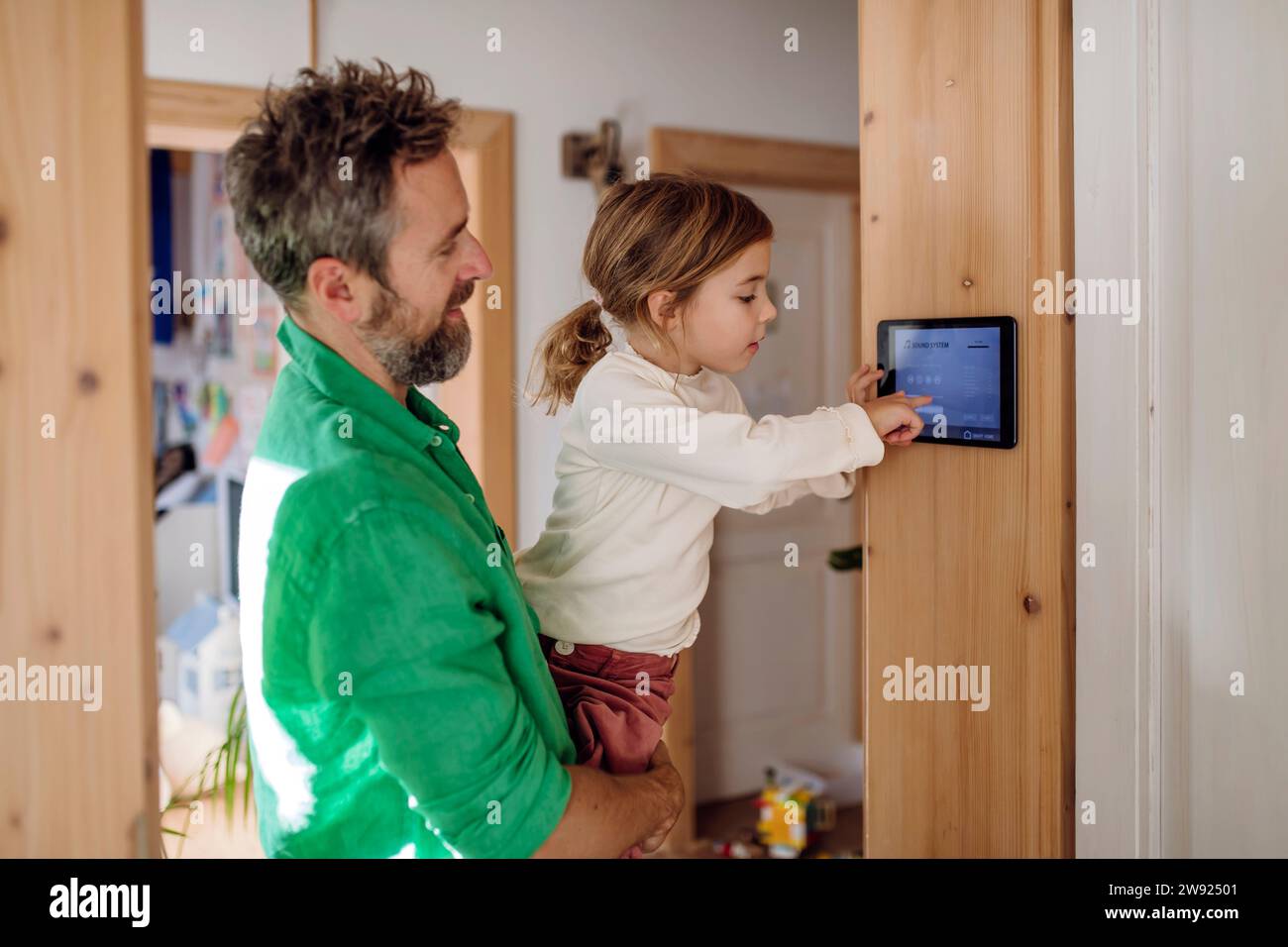 Tochter lernt mit Vater, die App für die Heimautomatisierung auf einem Tablet-PC anzupassen Stockfoto