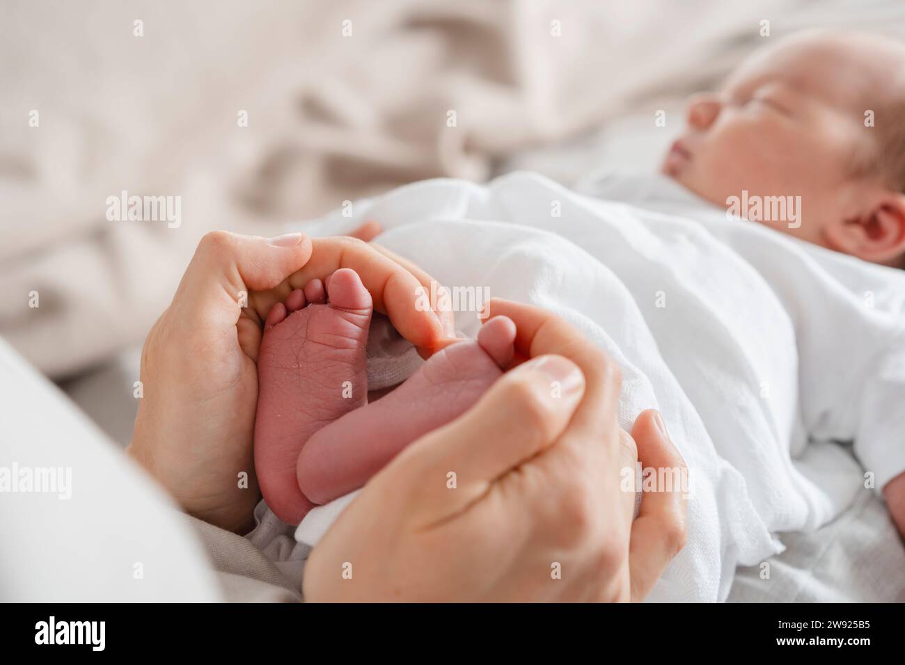 Mutter hält die Füße des neugeborenen Sohnes in der Hand Stockfoto