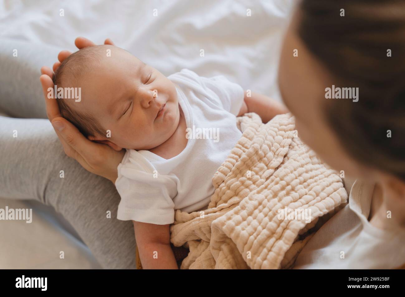 Niedliches Neugeborenes, das zu Hause in den Armen der Mutter schläft Stockfoto