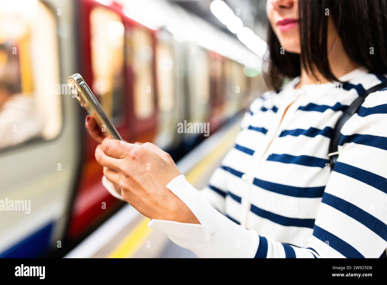 Frau, die ein Smartphone in der Nähe der U-Bahn am Bahnhof benutzt Stockfoto
