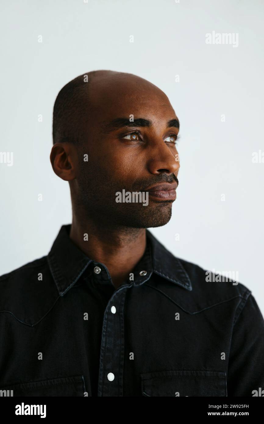 Mann trägt ein schwarzes Hemd vor weißem Hintergrund Stockfoto