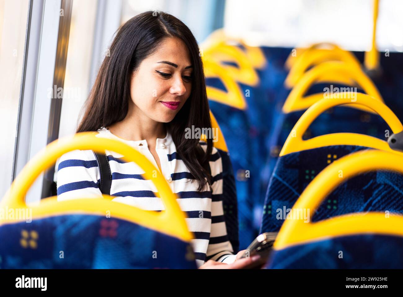 Lächelnde Frau mit Handy im Bus Stockfoto