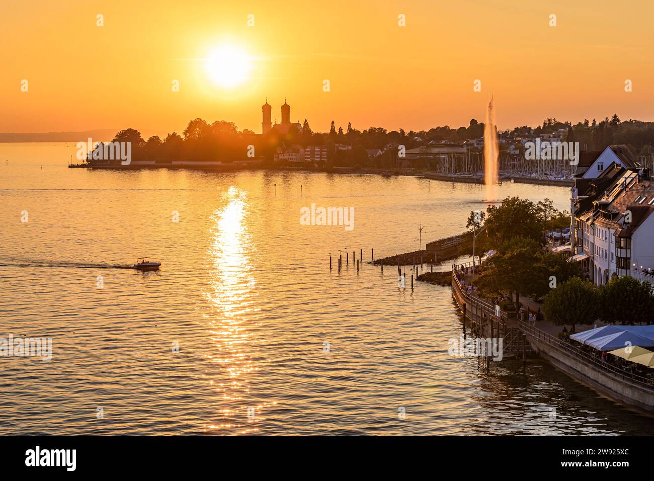 Deutschland, Baden-Württemberg, Friedrichshafen, Motorboot segelt in Richtung kleiner Hafen bei Sonnenuntergang Stockfoto