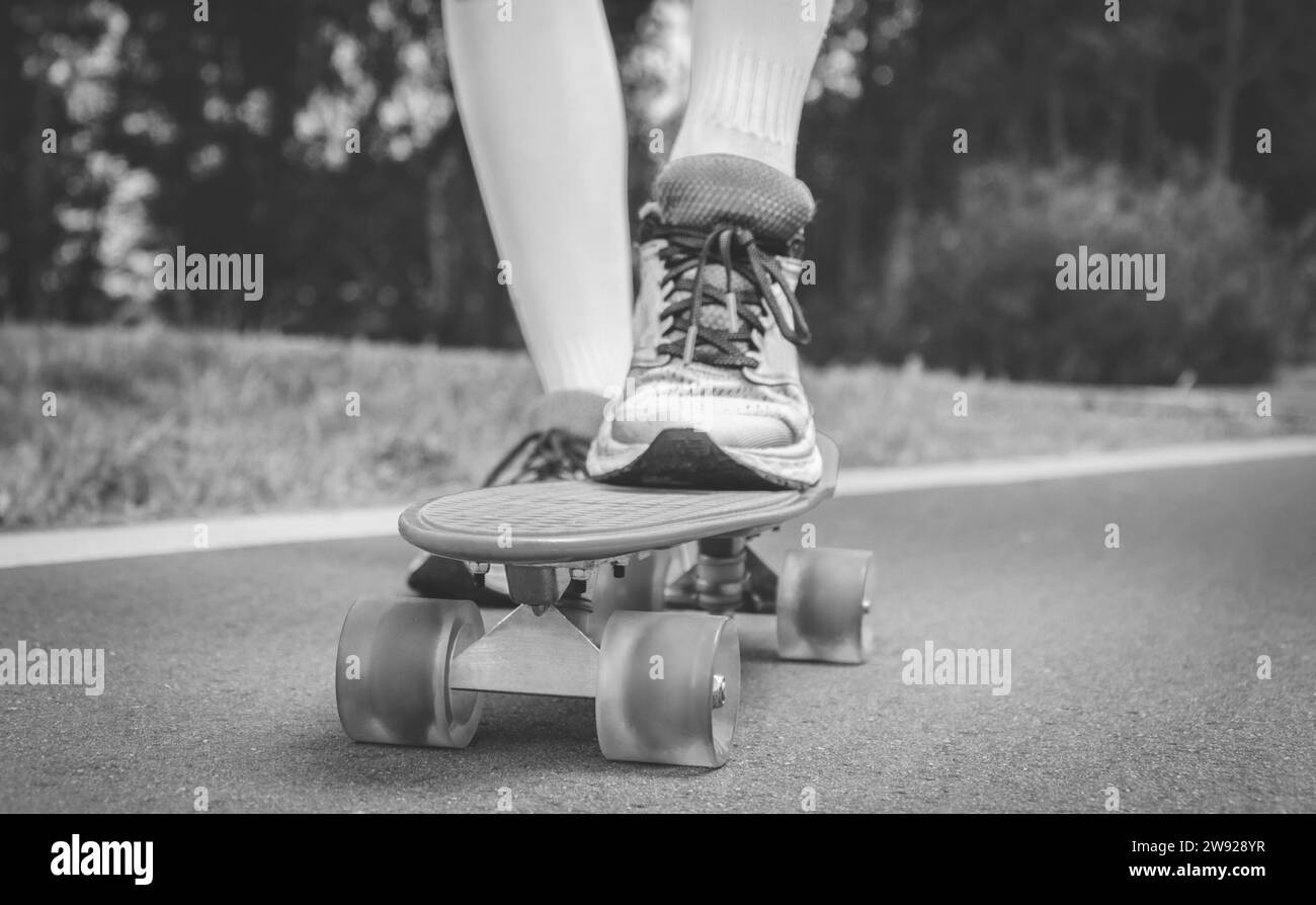 Bilder eines Beins, das auf einem Skateboard steht. Sonniger Abend im Park. Skateboarding-Konzept. Gemischte Medien Stockfoto