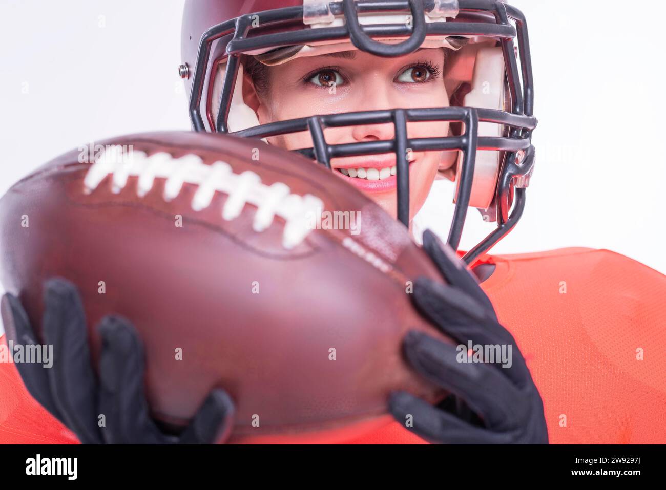 Porträt eines lächelnden Mädchens in der Uniform eines American Football-Mannschaftsspielers. Weißer Hintergrund. Sportkonzept. Gemischte Medien Stockfoto