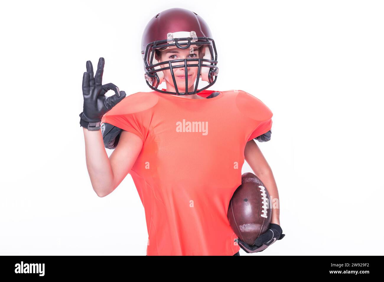 Eine Frau in der Uniform eines American Football-Mannschaftsspielers zeigt das OK-Zeichen. Sportkonzept. Gemischte Medien Stockfoto