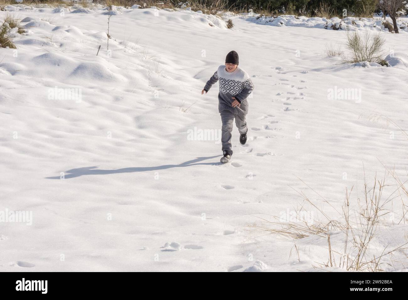 Junger Mann, der Spaß hat, in großem Schnee zu laufen Stockfoto