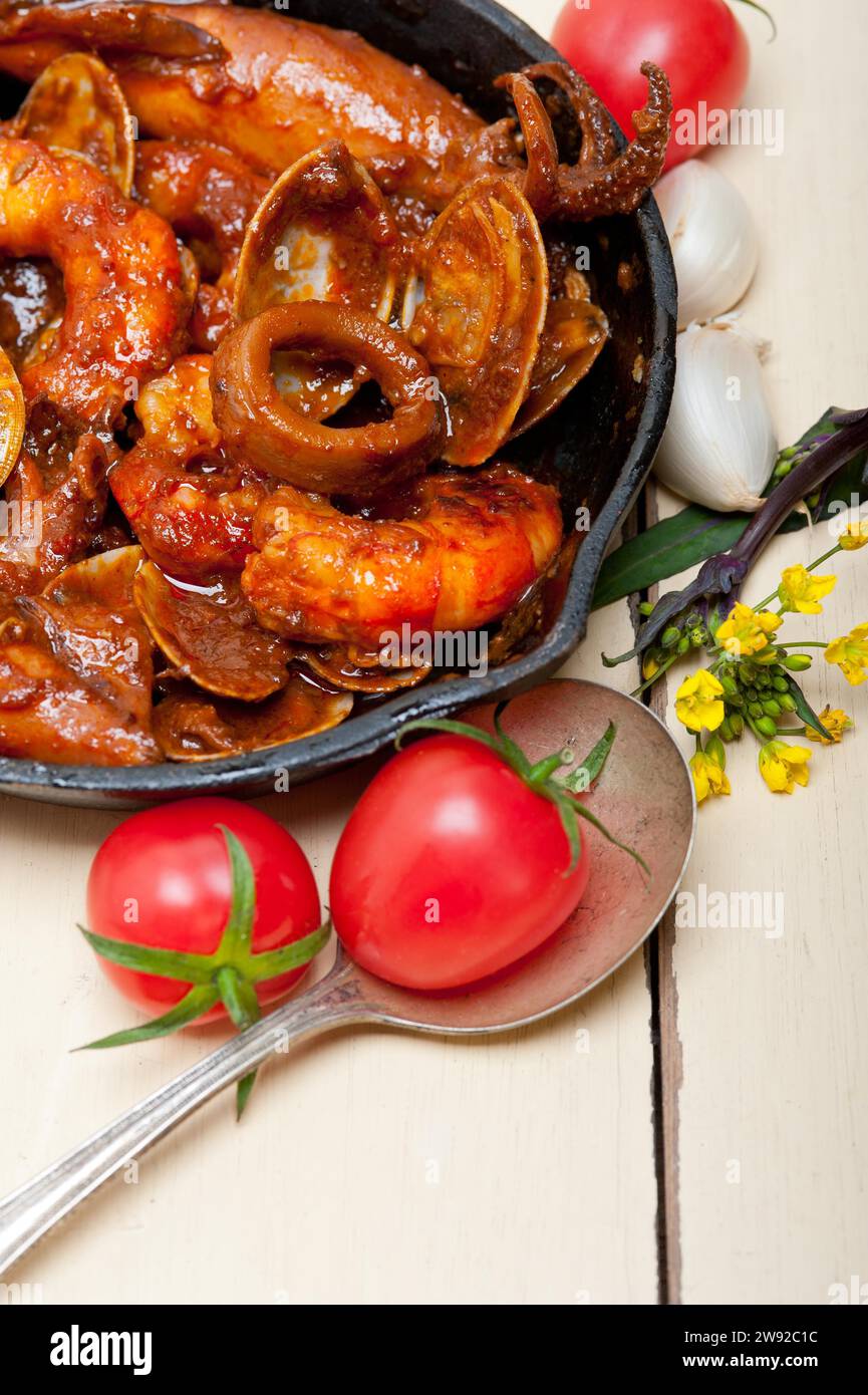 Frischer Eintopf mit Meeresfrüchten, zubereitet auf einer Eisenpfanne oder weißem rustikalen Holztisch, Lebensmittelfotografie Stockfoto