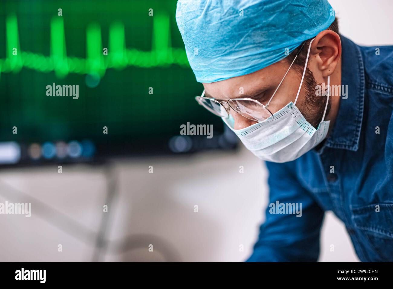 Porträt eines jungen professionellen Chirurgen, im Hintergrund ist ein Krankenhausoperationssaal Stockfoto