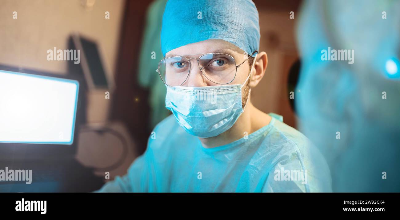 Porträt eines jungen professionellen Chirurgen, im Hintergrund ist ein Krankenhausoperationssaal Stockfoto