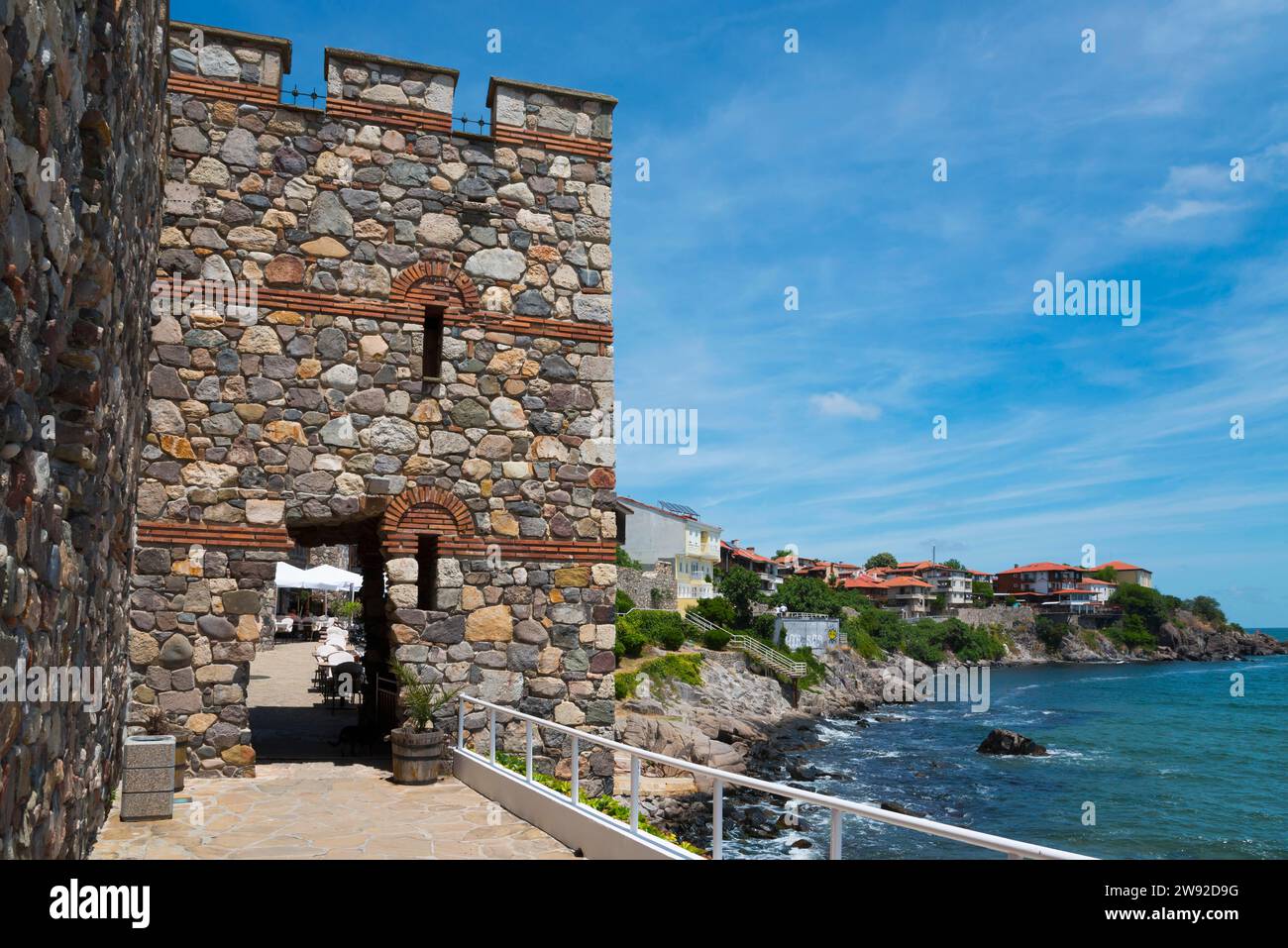 Alter Steinturm an einer felsigen Küste mit klarem blauem Himmel und ruhigem Meer, architektonisch-historischer Komplex, südlicher Festungsmauer und Turm, Altstadt Stockfoto