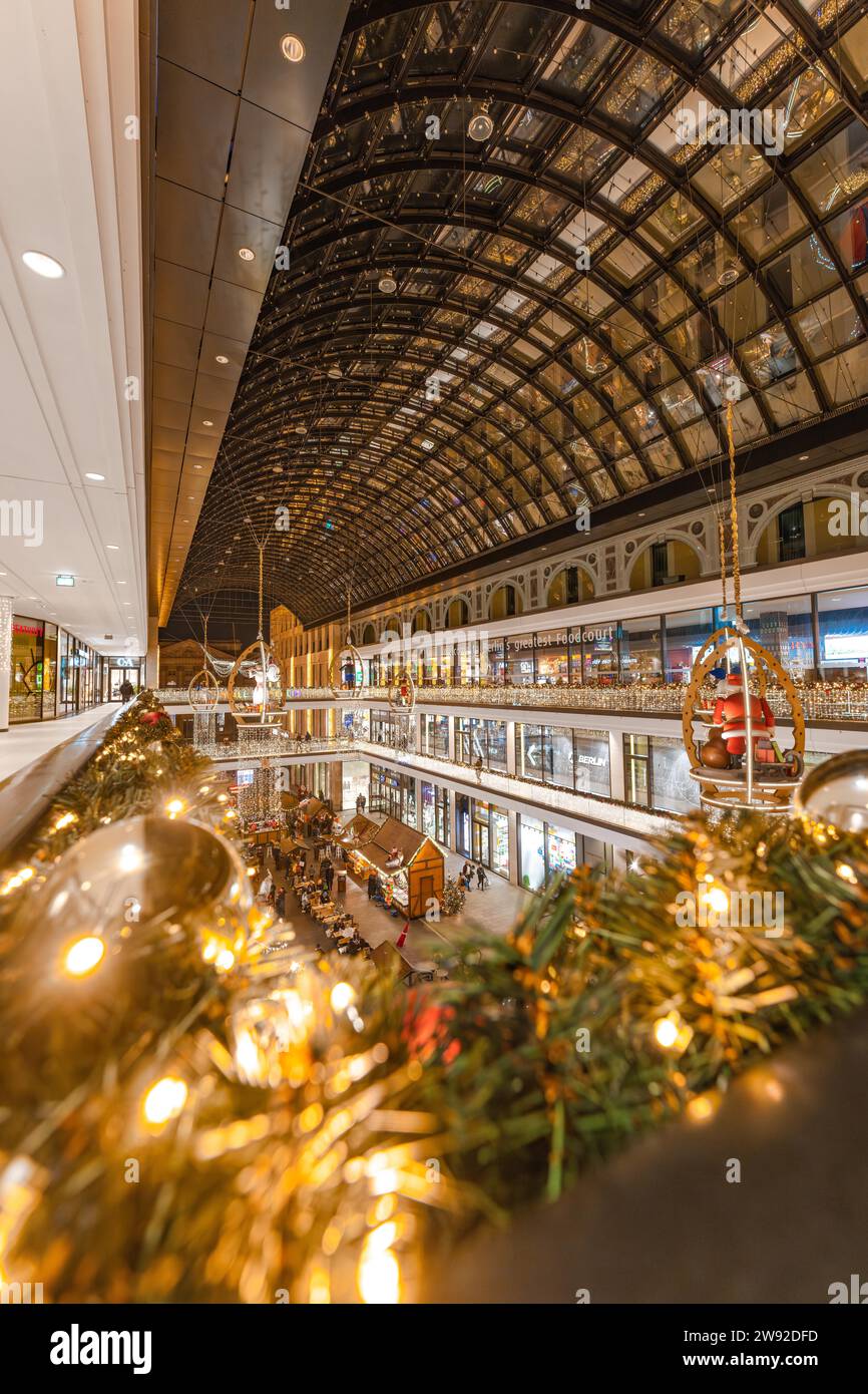 Innenraum eines Einkaufszentrums mit festlicher Weihnachtsbeleuchtung unter einem gewölbten Glasdach Stockfoto