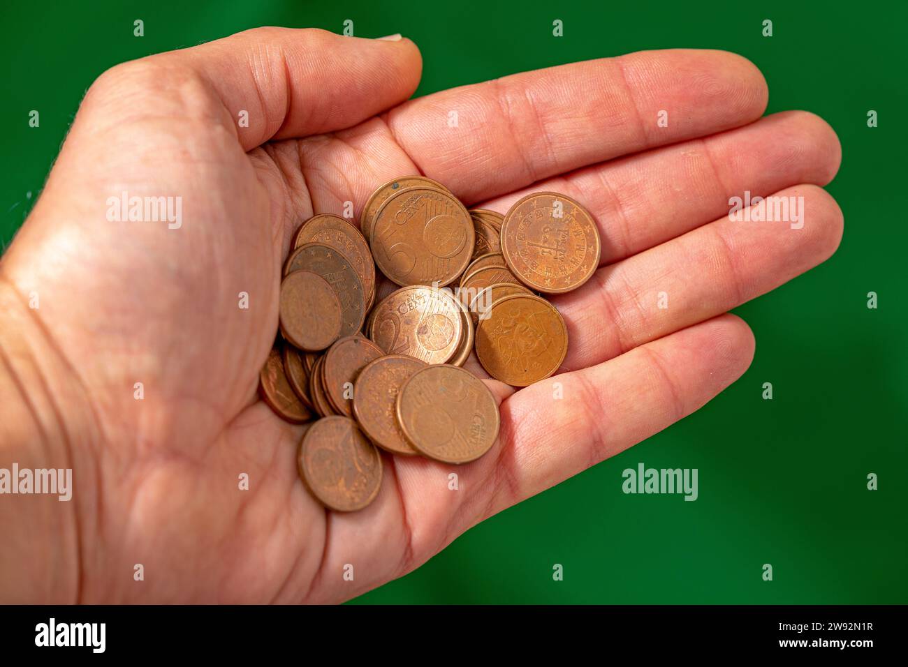 Hand voll mit kleinen braunen Euro-Münzen auf grünem Hintergrund. Stockfoto