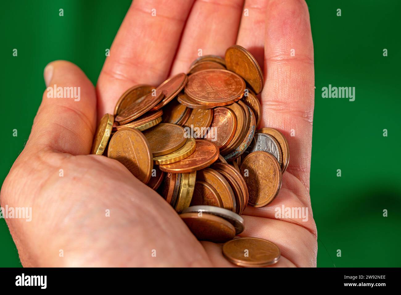 Hand voll mit kleinen braunen Euro-Münzen auf grünem Hintergrund. Stockfoto